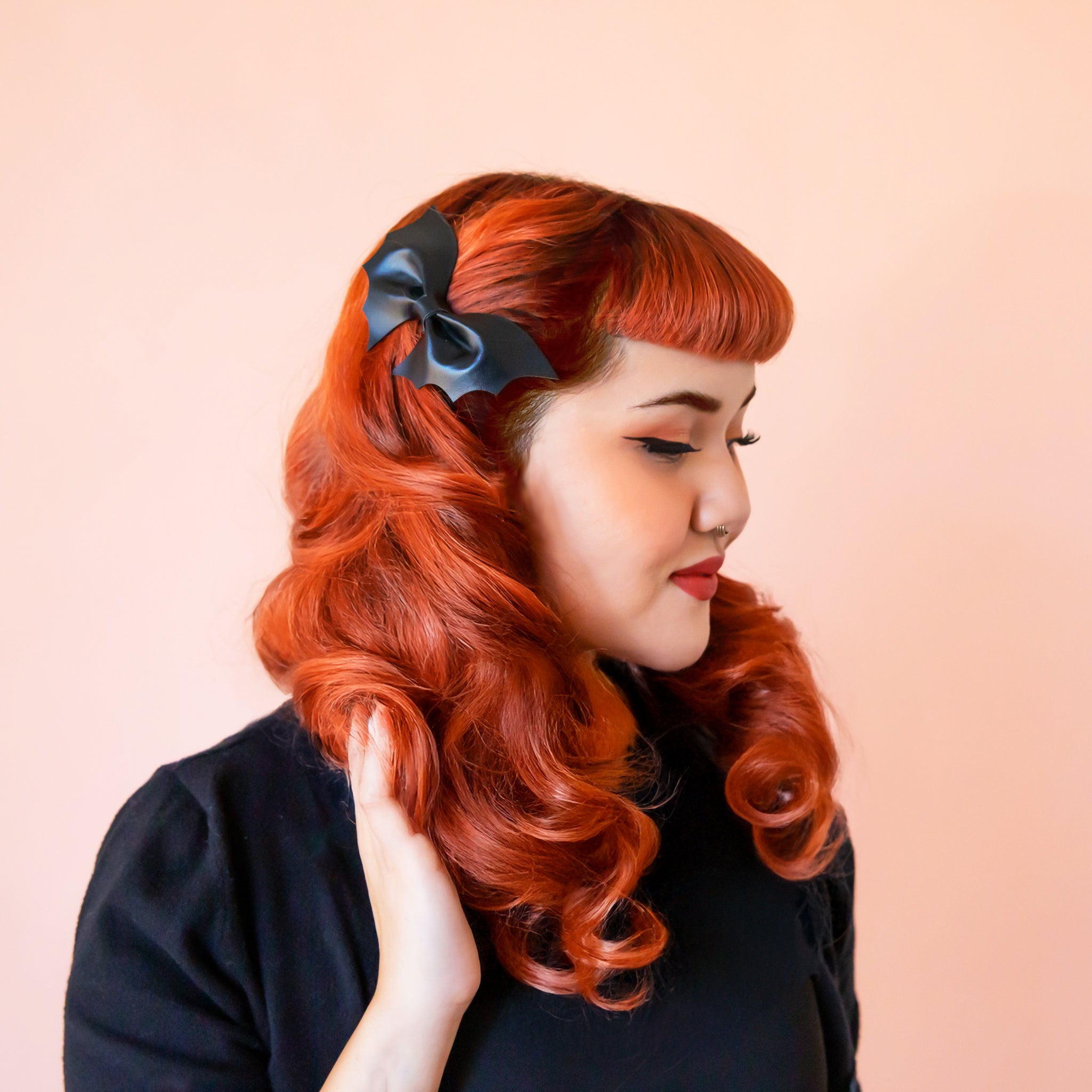 A red headed woman wears a black bat shaped hair clip.